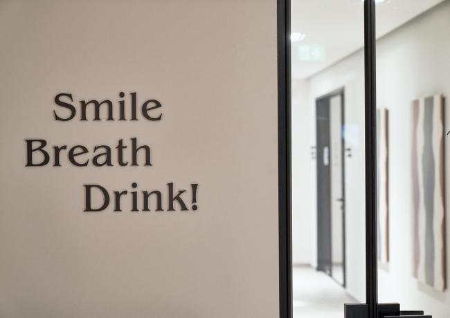 Segnale su una porta con le parole: Sorridi, Respira, Bevi!