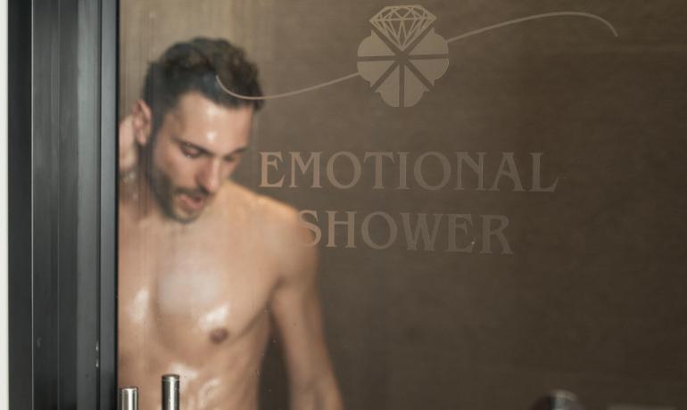 Man in emotional shower behind glass with writing.