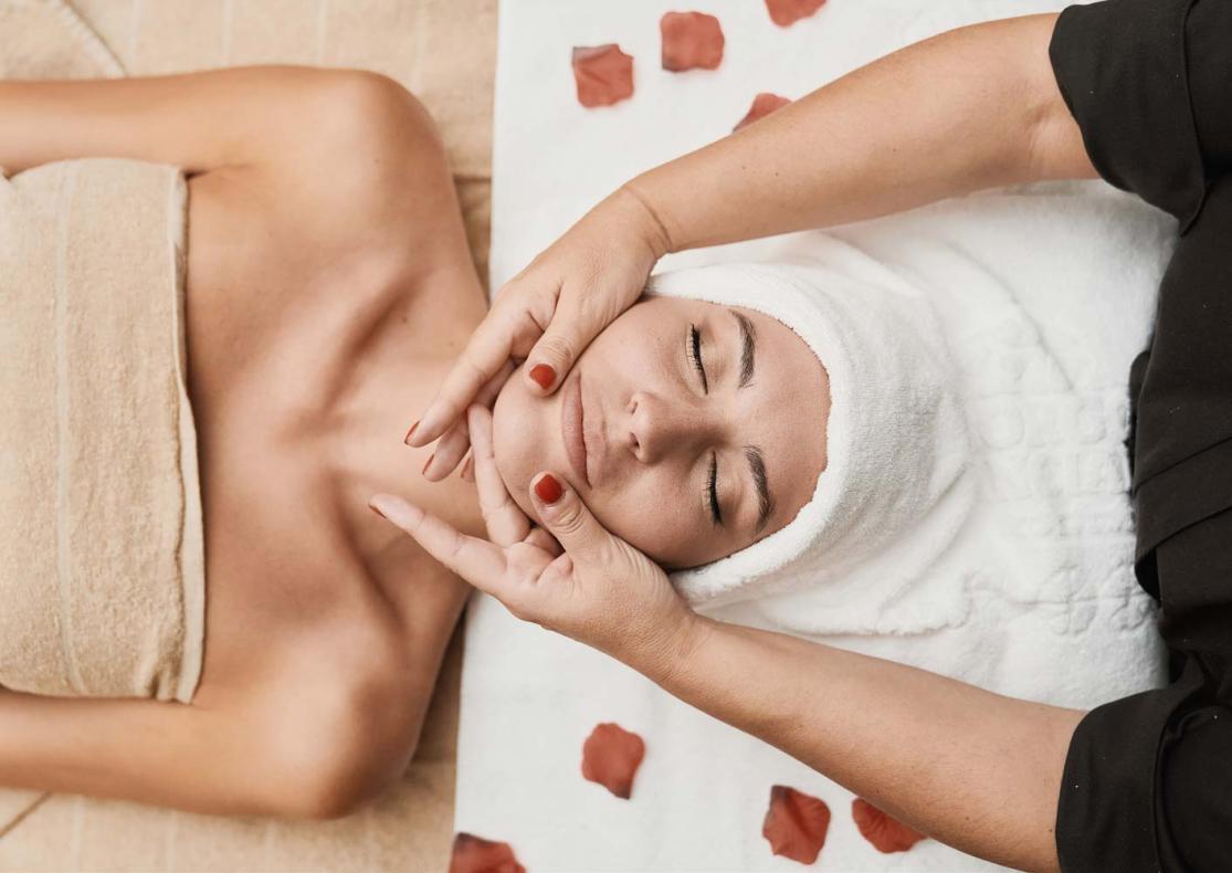 Massaggio rilassante del viso con petali di rosa.