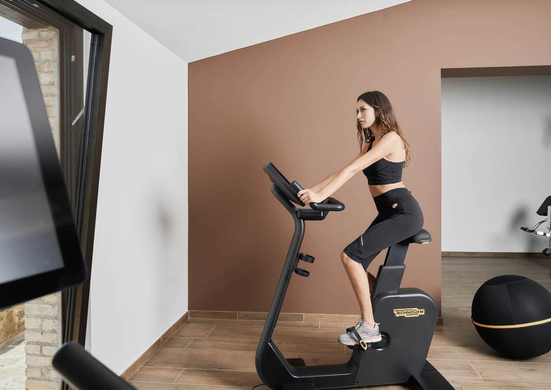 Donna su cyclette in palestra moderna con attrezzi fitness.
