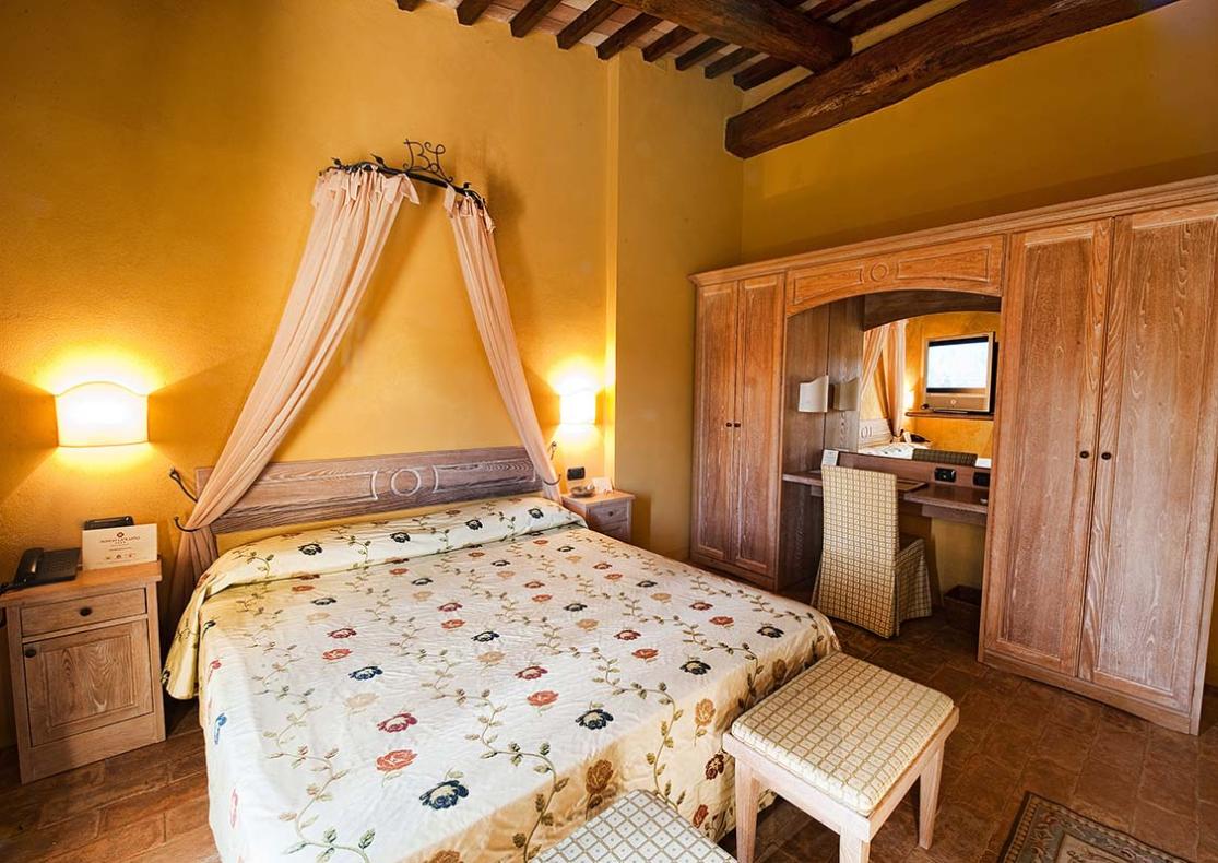 Camera accogliente con letto matrimoniale, divano e scrivania.