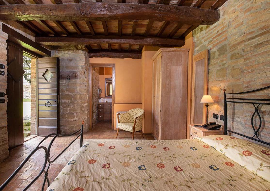 Camera da letto rustica con letto matrimoniale e finestra luminosa.