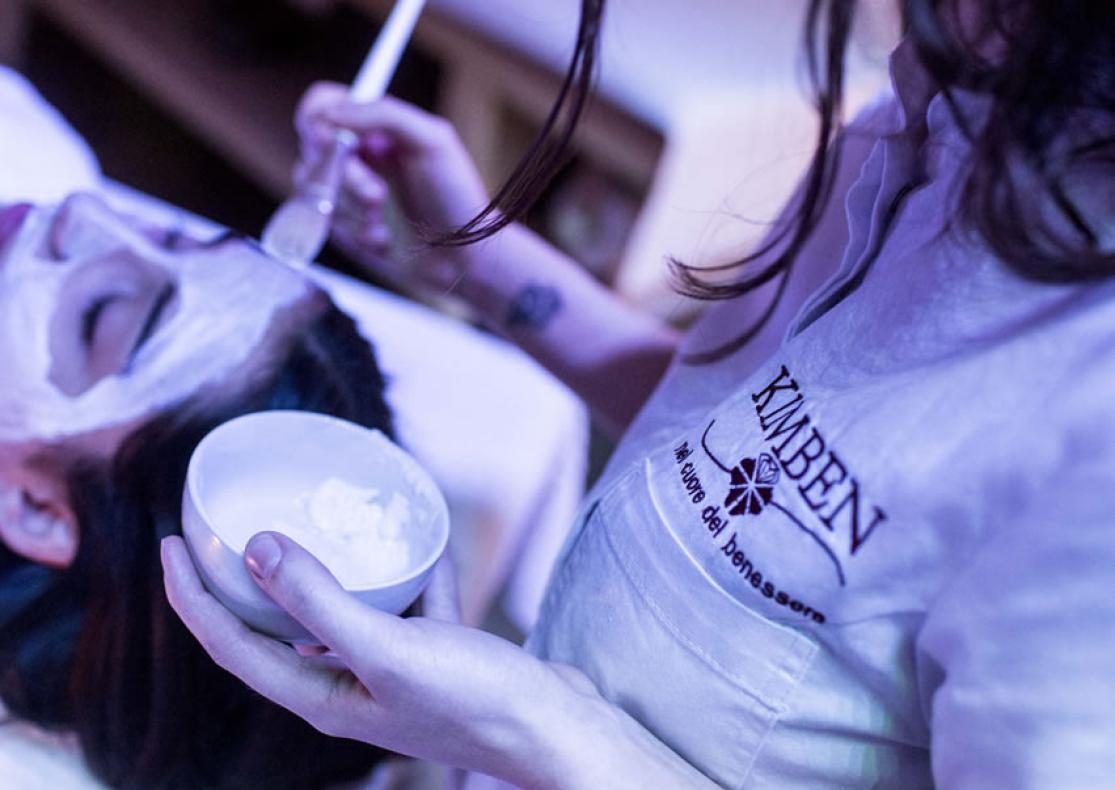 Trattamento viso rilassante con maschera bianca applicata da un'estetista.