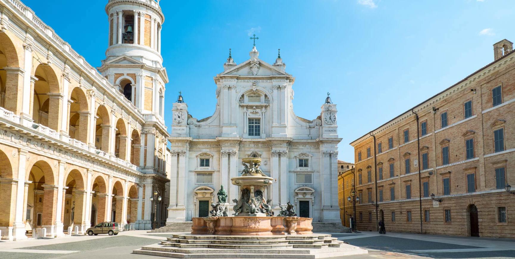 Square with fountain and basilica, historic architecture on a sunny day.