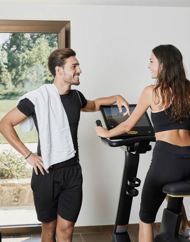 Due persone in palestra, una su una cyclette e l'altra con un asciugamano.