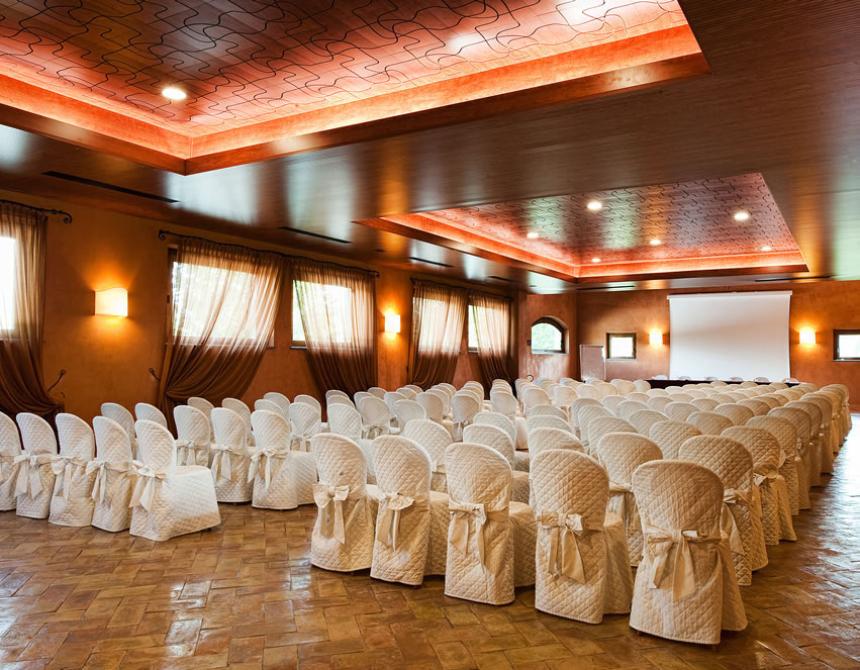 Sala conferenze elegante con sedie bianche e schermo per presentazioni.
